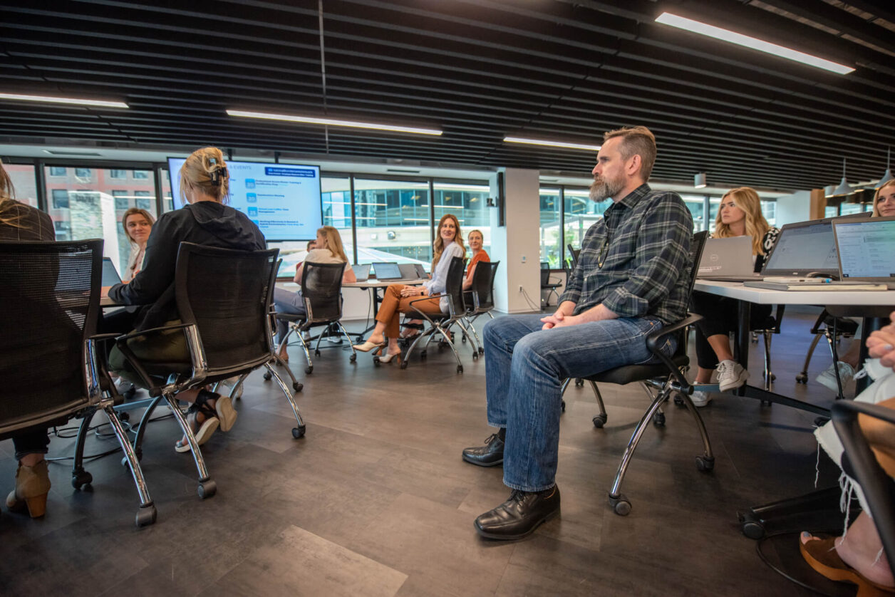 Group of professional colleagues in a Turnberry's casual business environment attend a meeting in open environment with multiple people at three tables