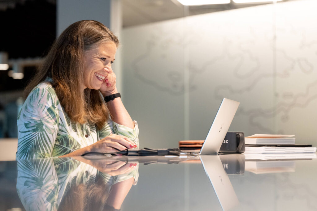Smiling mature woman takes part in a video call at Turnberry's modern offices