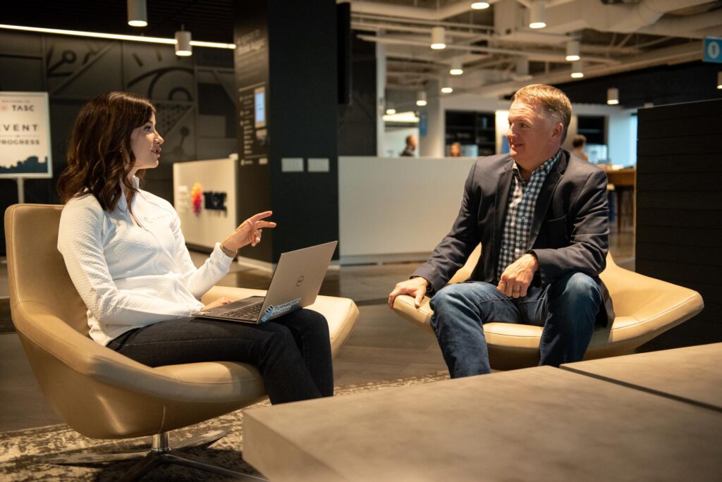 Young female professional meets with mature male professional in Turnberry's modern co-working space