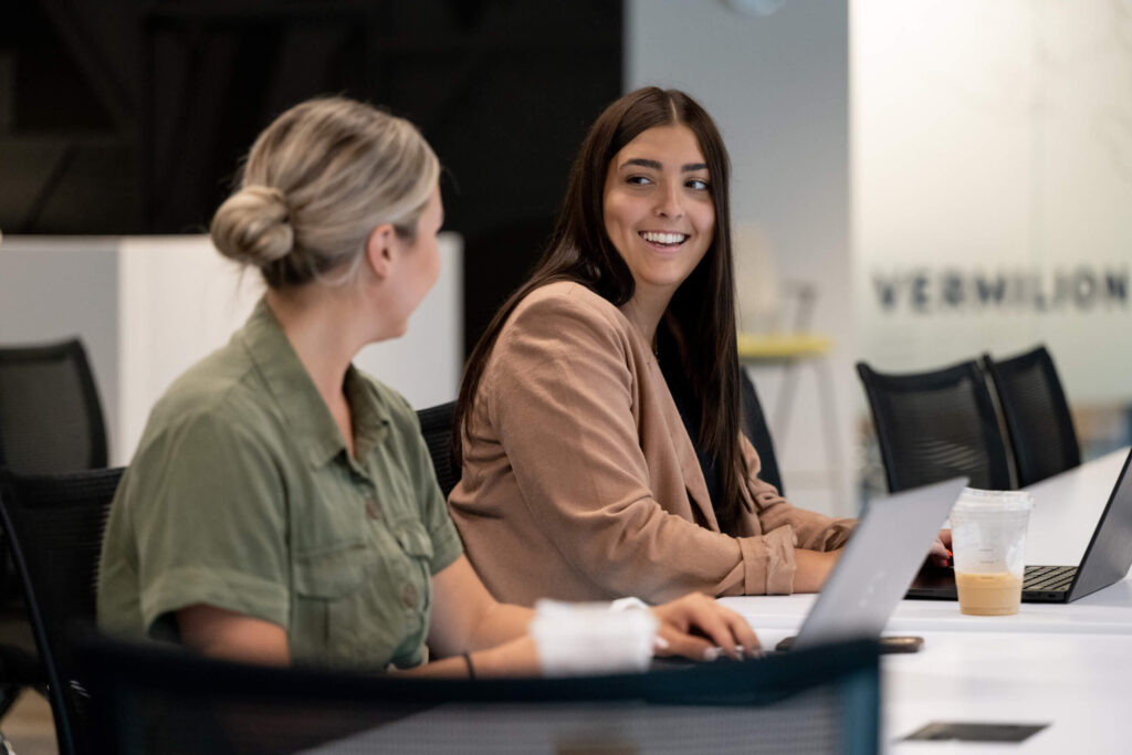 Two female professionals exchange glances while seated in Turnberry's modern, co-working space