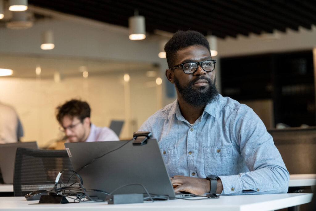 An African American man looks up from working on a laptop at Turnberry's modern offices