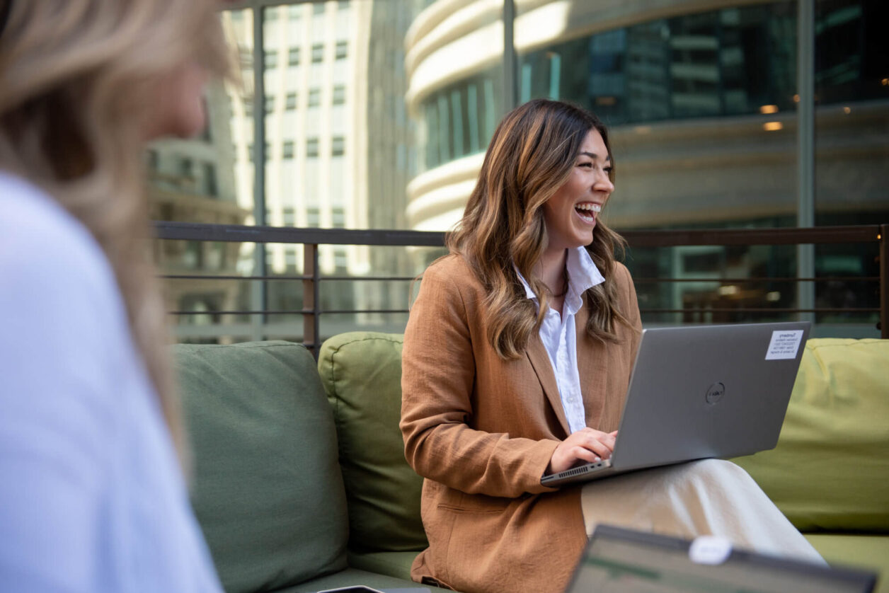 Female professional sits on Turnberry's rooftop co-working space laughing with colleagues