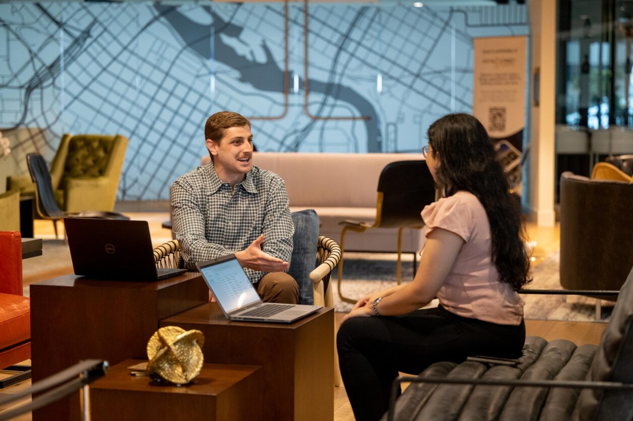 A young male professional talks to a young female professional at Turnberry's casual, modern offices