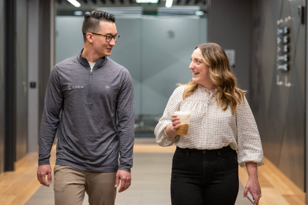 Turnberry Crew member walks with colleague carrying coffee in Turnberry's modern offices