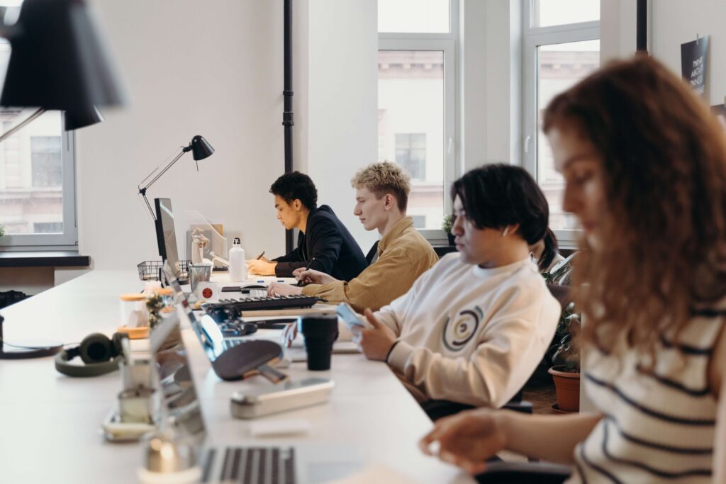 Photograph of young , mixed ethnicity male and female professionals working on laptops in a open office environment