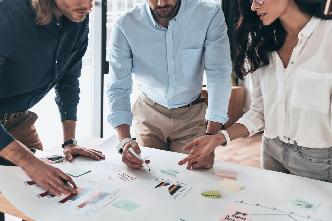 Three ethnically diverse professionals review analysis reports in a conference room