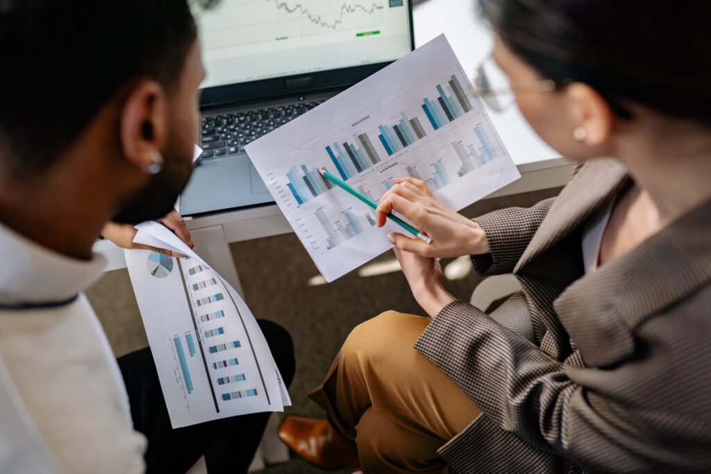 Two professionals review analysis bar chart on paper in shared office space