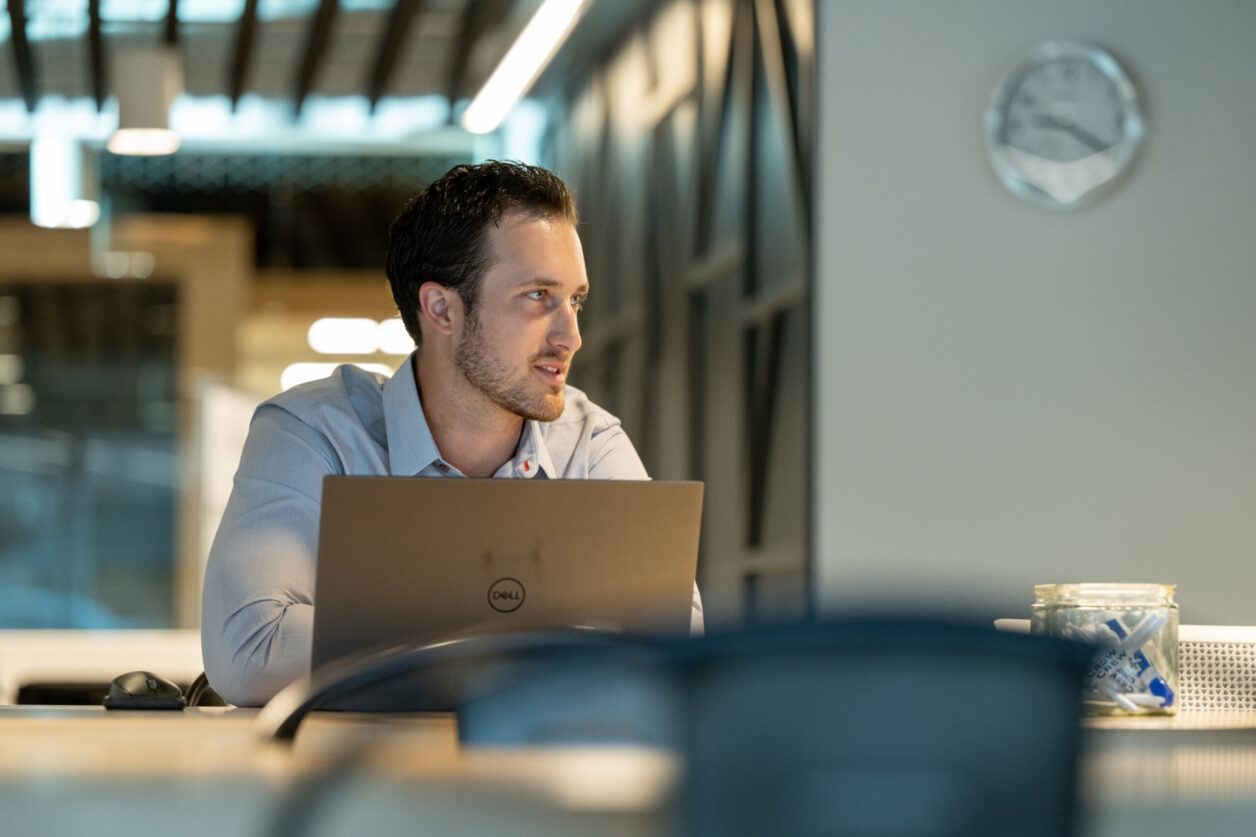 A man behind a laptop looks to the right at Turnberry's modern offices