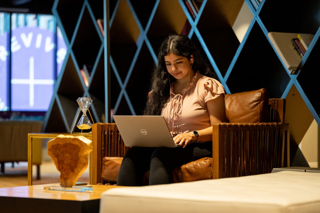 A professional young woman works on a laptop in Turnberry's modern offices in Minneapolis