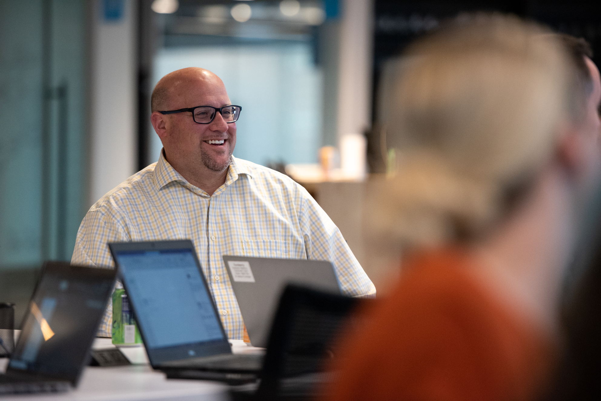 A professional man smiles during a group meeting at Turnberry's modern offices