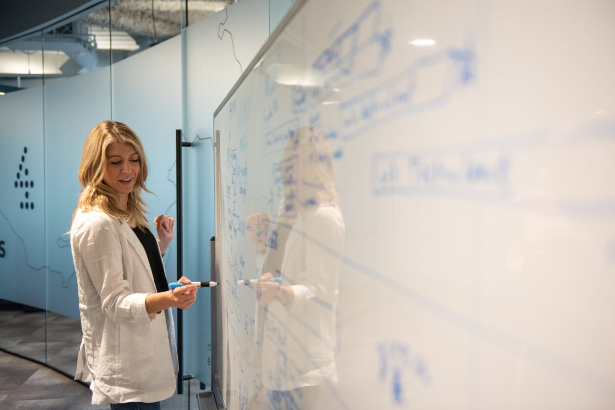 A Turnberry professional writes on a dry erase board at Turnberry's modern offices