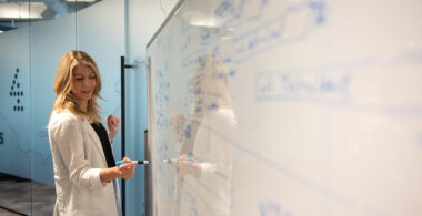 A Turnberry professional writes on a dry erase board at Turnberry's modern offices