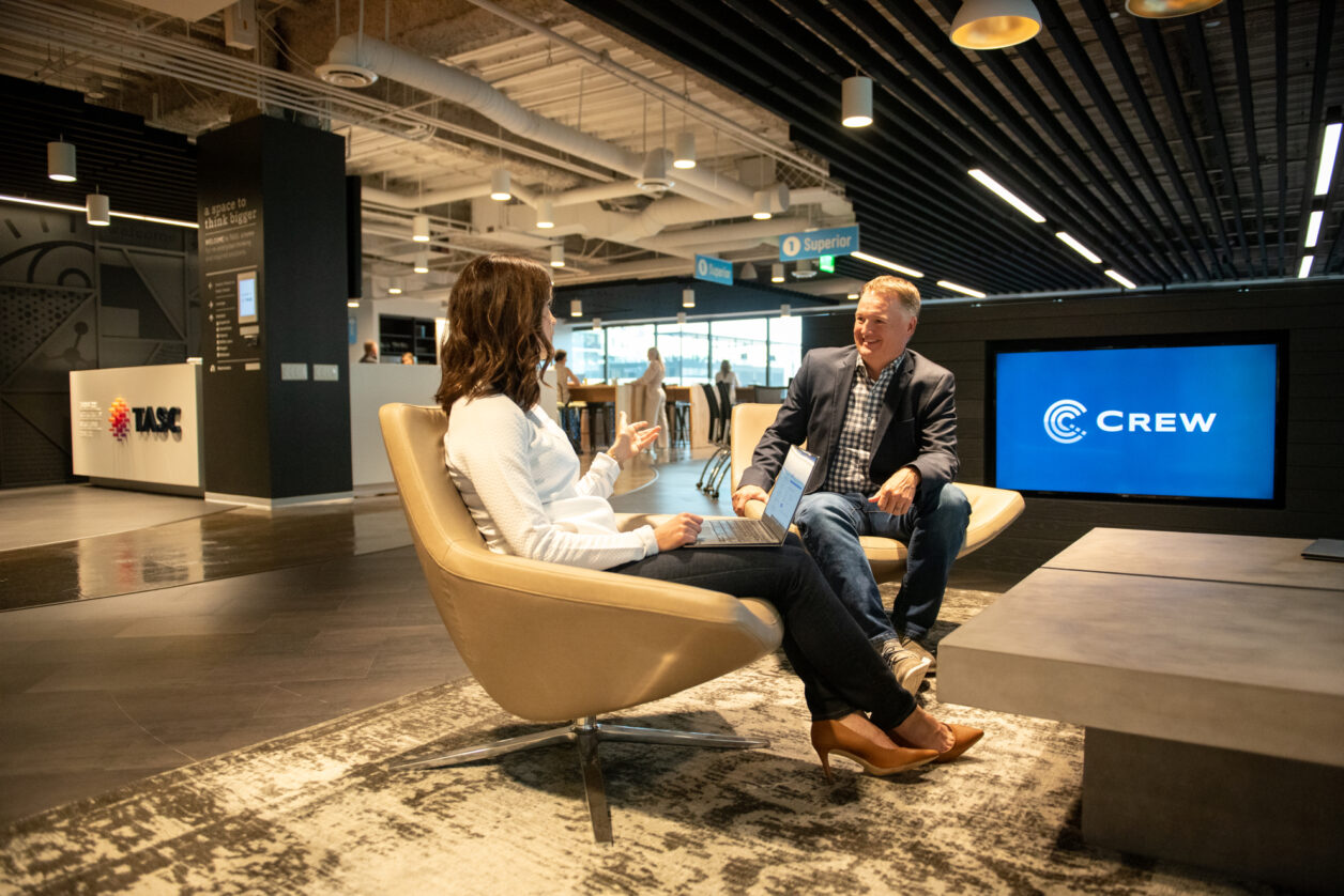 A mid-career professional woman converses with a mature male colleague at Turnberry's modern offices in Minneapolis