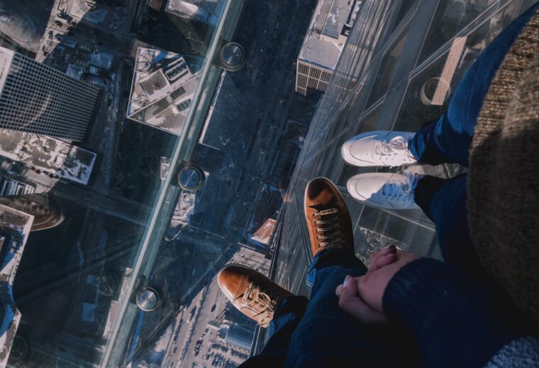 Two people hold hands while standing on the Skydeck at Willis Tower, Chicago to convey why transparency is so scary