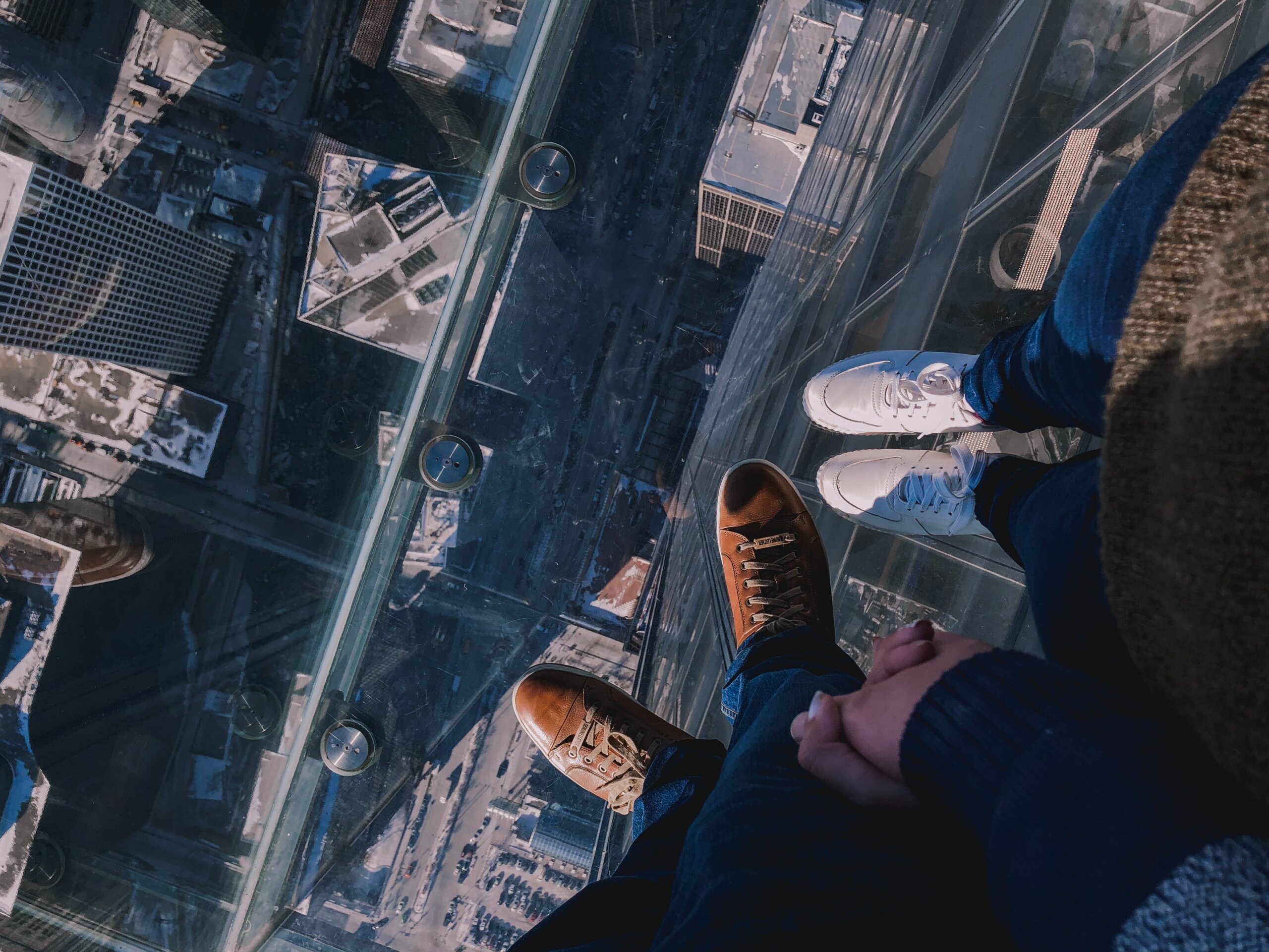 Two people hold hands while standing on the Skydeck at Willis Tower, Chicago to convey why transparency is so scary